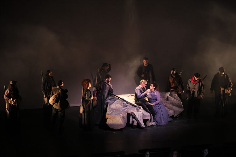 Center from left: Mere Oliveira as Pilar, Gustavo Rocha Ribeiro as Pablo,  Michael Axelsson as Robert Jordan, Isabel Quintela Soares Martins as Maria, with ensemble. Photo by Robson Cesco.